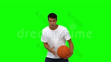 男子带着<strong>篮球</strong>在绿色的屏幕上<strong>运球</strong>